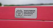 Eine pinke Bank mit einem Schild über Hochwasserschutz.